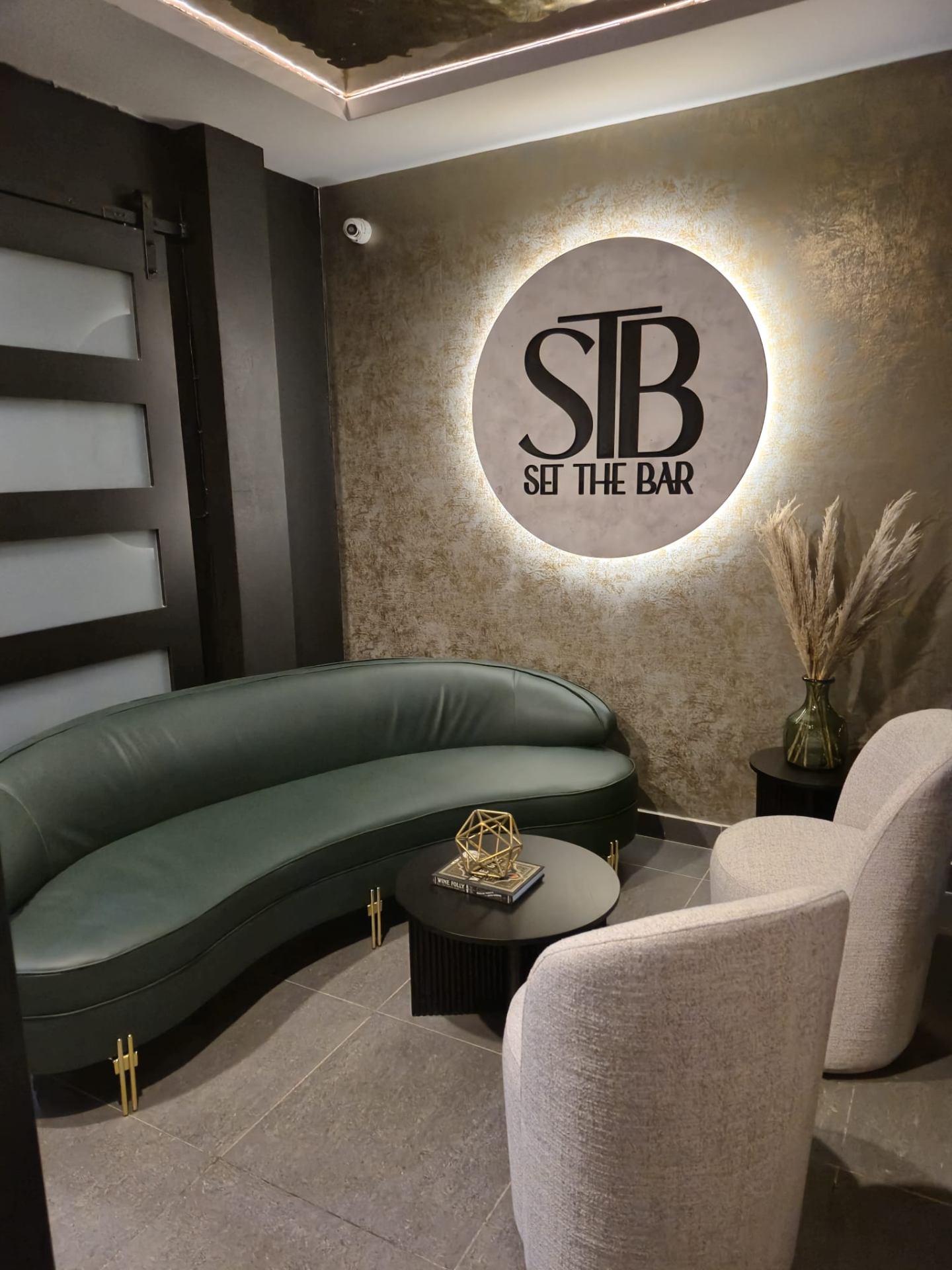 Backlit STB Set The Bar circular sign in a lounge